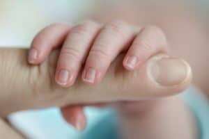Newborn hand around Mom's finger