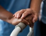 care provider nurse hand on elderly man's hand